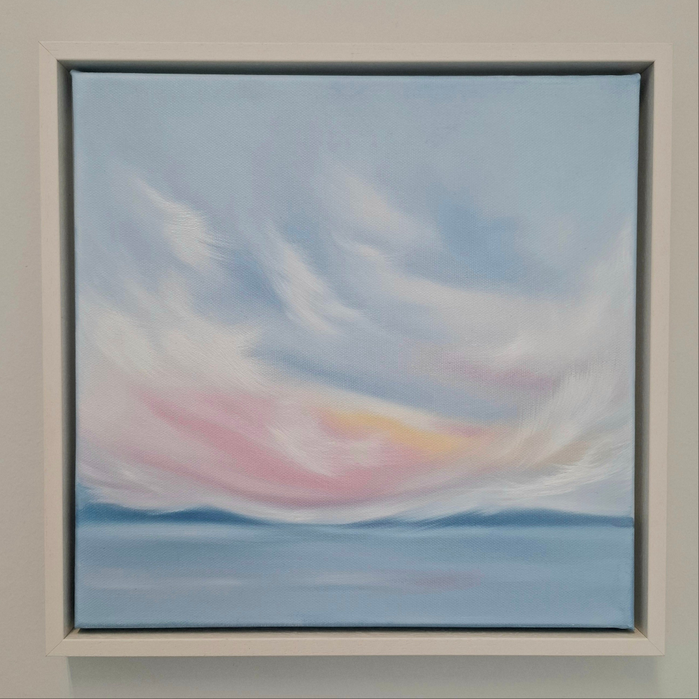 Oil painting. A skyscape of pink blue and white with blue mountains in the distance and water in the foreground. 
