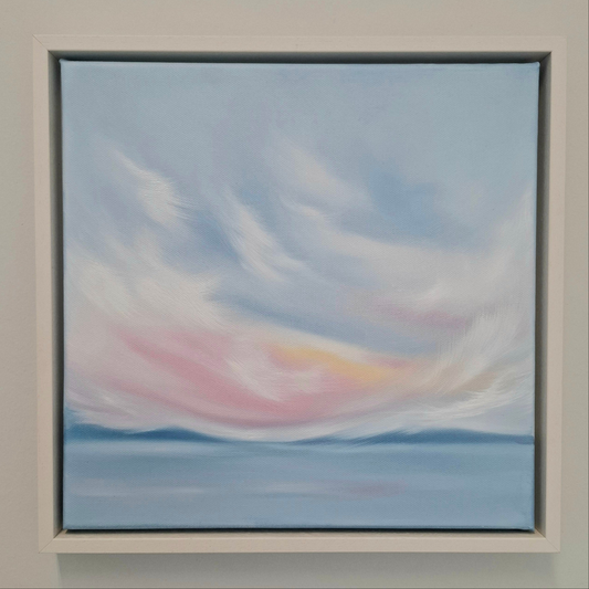 Oil painting. A skyscape of pink blue and white with blue mountains in the distance and water in the foreground. 